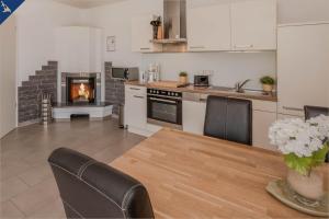 a kitchen with a table and a fireplace at Villen am See - Villa Petra Whg Ahlbeck in Korswandt