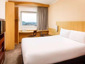 a hotel room with a large white bed and a desk at ibis Nottingham Centre in Nottingham