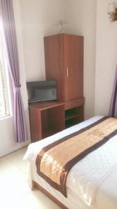 Huy Hoang Airport في هانوي: غرفة نوم مع سرير وخزانة مع تلفزيون