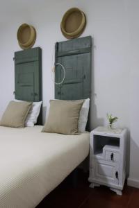 twee bedden met groene hoofdeinden naast een nachtkastje met een tafel bij Casa dos Marias in Elvas