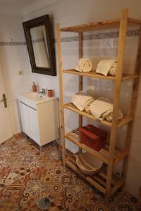 a bathroom with a shelf with towels and a sink at Casa dos Marias in Elvas