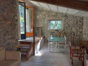 a living room with a table and a stone wall at Bergerie La Roche in Caudiès-de-Fenouillèdes
