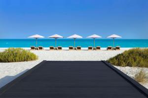 una pasarela a la playa con sillas y sombrillas en Park Hyatt Abu Dhabi Hotel and Villas, en Abu Dabi