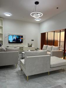 a living room with couches and a flat screen tv at شالية رواء كبلز in á¸¨arÄdÄ«