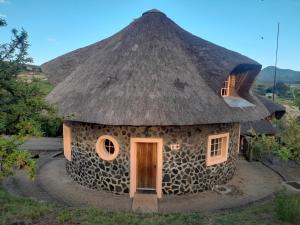 Cette petite maison en pierre est dotée d'un toit de chaume. dans l'établissement Liphofung Cave, Chalets, à Butha-Buthe