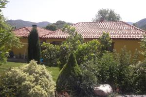 una casa amarilla con muchos árboles y arbustos en El Refugio de Santi, en Butrera