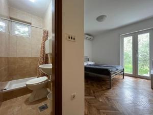 a bathroom with a toilet and a sink and a bed at Apartments Babić in Rab