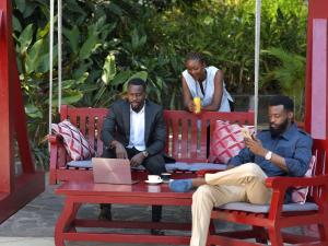 a group of three men sitting at a table with a laptop at Pullman Kinshasa Grand Hotel in Kinshasa