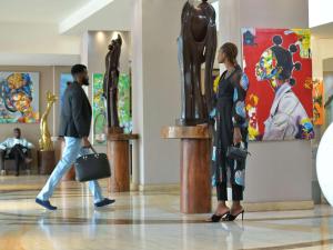 un homme et une femme se promènent devant une statue dans un musée dans l'établissement Pullman Kinshasa Grand Hotel, à Kinshasa