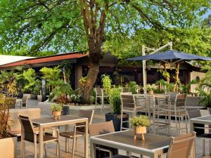 un patio al aire libre con mesas, sillas y un árbol en Pullman Kinshasa Grand Hotel en Kinshasa