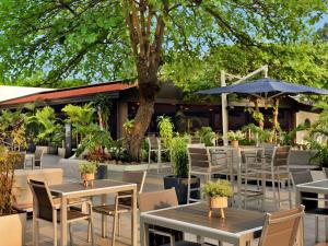 an outdoor patio with tables and chairs and a tree at Pullman Kinshasa Grand Hotel in Kinshasa