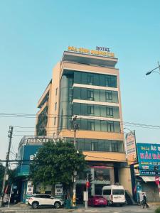 Ðông Hà的住宿－Khách sạn HOÀ BÌNH QUẢNG TRỊ，一座高大的建筑,前面有汽车停放