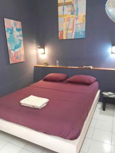 una camera da letto con un letto grande con lenzuola viola di La Casa Homestay a Senggigi