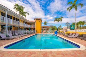 a swimming pool in front of a hotel with palm trees at Quality Inn & Suites Airport-Cruise Port Hollywood in Hollywood