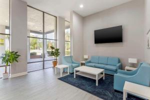 a living room with two blue chairs and a tv at Quality Inn Gainesville near University in Gainesville