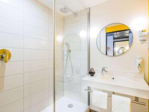 uma casa de banho branca com um chuveiro e um lavatório. em ibis Styles Paris Meteor Avenue d'Italie em Paris