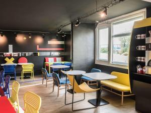 - un restaurant avec des tables et des chaises colorées dans une chambre dans l'établissement ibis Styles Lyon Bron Eurexpo, à Bron