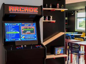 a video game machine in a restaurant with a table at ibis Styles Lyon Bron Eurexpo in Bron