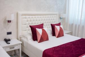 ein Schlafzimmer mit einem weißen Bett mit roten und weißen Kissen in der Unterkunft Hotel San Pietro in Maiori