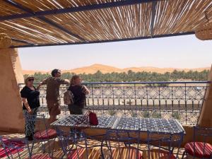 um grupo de pessoas de pé numa varanda com vista em Riad Les jardins de Merzouga em Merzouga