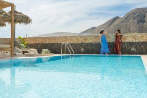 佩里薩的住宿－Loukas & Emma Houses，两个女人站在游泳池旁边