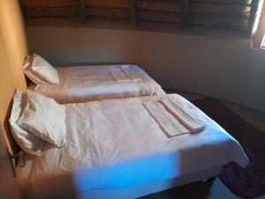two twin beds in a bedroom with a blue light at Liphofung Cave, Chalets in Butha-Buthe
