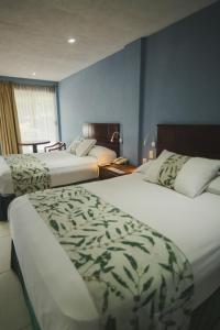 a hotel room with two beds and a window at Villa Esmeralda in San Juan Bautista Tuxtepec