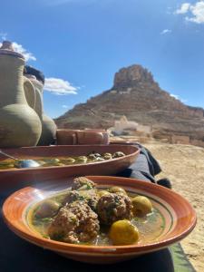 dos platos de comida en una mesa con una montaña en el fondo en Ecogite Guermessa, en Ghomrassen