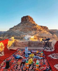 a table with food and drinks in front of a mountain at Ecogite Guermessa in Ghomrassen