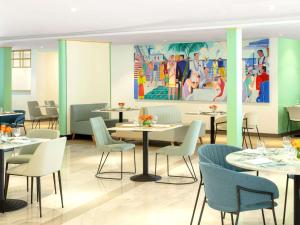un ristorante con tavoli, sedie e un dipinto di Queen Elizabeth 2 Hotel a Dubai