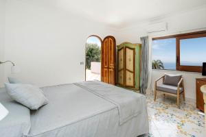 a bedroom with a bed and a chair and a window at Hotel Il Girasole in Anacapri