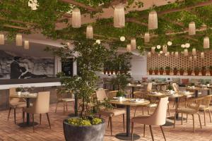 a restaurant with tables and chairs and plants at Cala San Miguel Hotel Ibiza, Curio Collection by Hilton, Adults only in Puerto de San Miguel