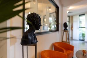 Un busto di testa su un banco vicino a una sedia arancione di Hotel Acapulco a Forte dei Marmi