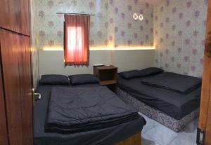 - 2 lits dans une petite chambre avec fenêtre dans l'établissement CELLINO HOMESTAY, à Probolinggo