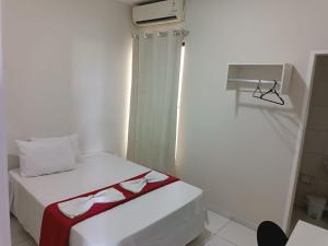 ein kleines Schlafzimmer mit einem weißen Bett und einer roten Decke in der Unterkunft POUSADA MEDITERRÂNEO in Lagarto