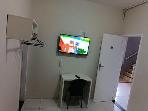 a room with a desk and a tv on a wall at POUSADA MEDITERRÂNEO in Lagarto