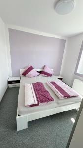 uma cama branca com lençóis e almofadas cor-de-rosa e branco em Berzi Ferienwohnung 002 Görlitz em Markersdorf