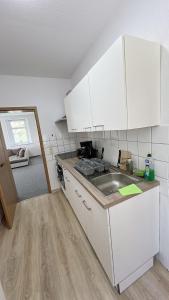 uma cozinha com armários brancos e um lavatório em Berzi Ferienwohnung 002 Görlitz em Markersdorf