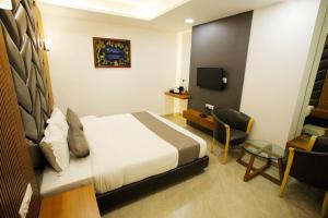 a bedroom with a bed and a desk and a chair at Hotel The Grand in Indore
