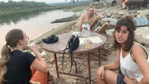 two women and a man sitting at a table by a river at Hong Qi Hotel in Chitwan
