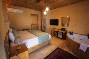 um quarto com uma cama, uma banheira e uma televisão em Milagro of Cappadocia em Üçhisar