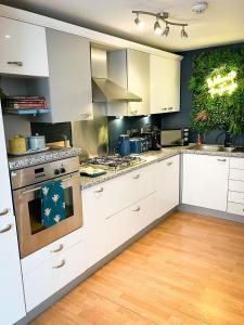 a kitchen with white cabinets and a stove top oven at Jungle Escape, City Apartment with Parking & Terrace in Chester