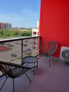 een balkon met 2 stoelen en een rode muur bij Apartament nemaipomenit, nou, in Complex Rezid Ared in Arad