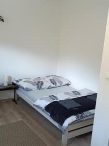 a bed in a room with a white wall at Staś-przy szkole nr3 w Skawie in Skawa
