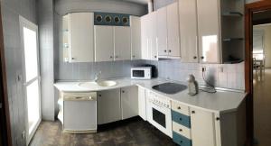 a kitchen with white cabinets and a sink and a microwave at Alojamiento Mirasierra II in Torre del Campo +11 photos