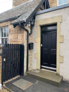a black door on the side of a brick house at Lower Tweedknowe - ground floor villa Melrose in Melrose