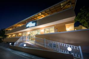 a building with a sign on the side of it at night at Anemona Beach Hotel in Argasi