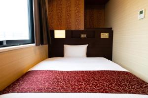 a bedroom with a bed with a red blanket at Hotel. Links Namba in Osaka