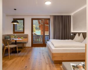 ヴァイセンゼーにあるFerienhof Neusacher Moserのベッド、テーブル、ダイニングルームが備わるホテルルームです。