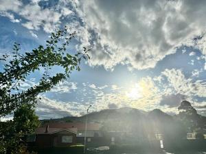 ein wolkiger Himmel mit Sonne und Bergen im Hintergrund in der Unterkunft 1BR Apartment - Walk to City (1 Queen Bed) in Hobart
